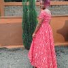 Customizable Kitenge dress with red and white patterns, high-low hemline, and durable fabric. Supports communities in Africa.