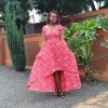 Customizable Kitenge dress with red and white patterns, high-low hemline, and durable fabric. Supports communities in Africa.