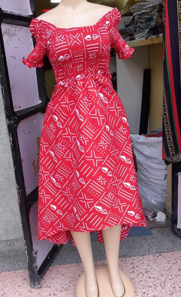 Customizable Kitenge dress with red and white patterns, high-low hemline, and durable fabric. Supports communities in Africa.