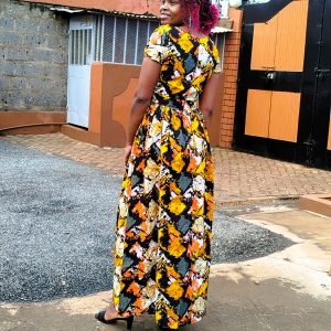A colorful, custom-made Kitenge maxi dress in yellow, orange, and black patterns, tailored for comfort and durability.